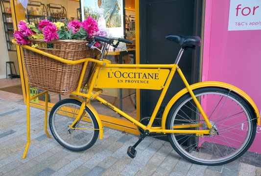 Bracknell, England - February 18, 2020: A bicycle with a basket of flowers painted with the brand name and colors of L'Occitane outside their store in Bracknell England