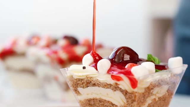 Extreme close up pour sweet strawberry sauce on dessert with whipped cream. 4k Dragon RED camera