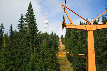 Cable car in the ski area of Bulgaria in summer. Yellow chair ski lift is among the green firs and...