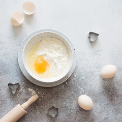 Wheat flour and raw eggs on a gray stone backgound