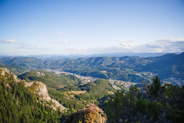Obraz premium Panoramic top view of the green mountain valley from the top of the cliff in autumn in the Balkans. Mountain village in the Rhodope mountains in Bulgaria