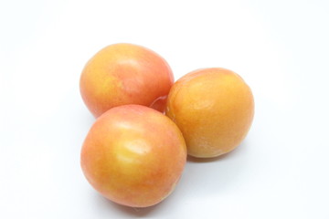 Beautiful delicious orange plums are located on a white background