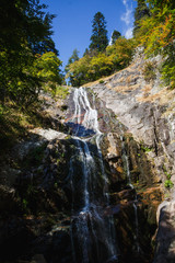 Streams of the waterfall fall from the rock and sparkle in the sun among the greenery. Attractions of Bulgaria - Krushuna waterfalls and mountain trail in Smolyan