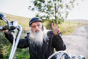 A senior man traveller with motorbike in countryside.