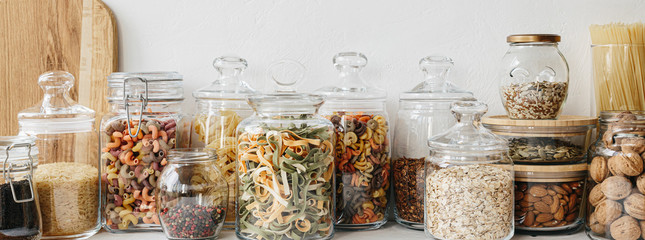 Various cereals and seeds in glass jars on the white textured background. Kitchen interior ideas. Eco friendly kitchen, zero waste home concept