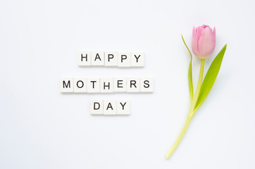 Text Happy Mother's Day made of wooden cubes with tulip flower isolated on white. Flat lay