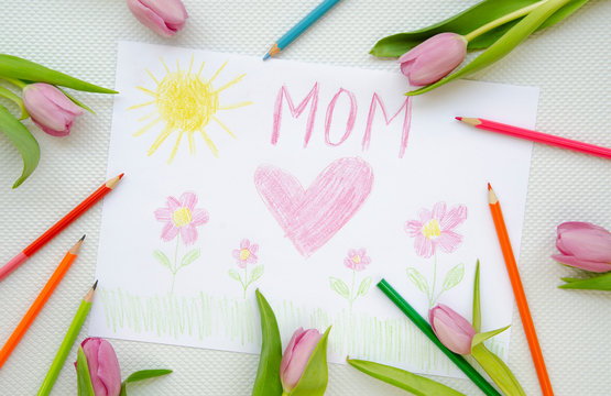Top view child's drawing I love mom frame with colorful pencils and tulips. Mothers day concept