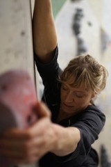 Obraz premium Female athletic climber climbing, bouldering at indoor boulder rock hall