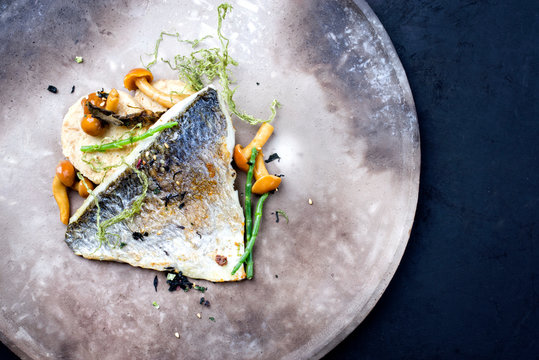 Gourmet gebratenes Doraden Fisch Filet mit Scheiben von Semmel Kn&ouml;del, Meeresbohnen und Algen als Draufsicht auf einem Modern Design Teller mit Textfreiraum rechts