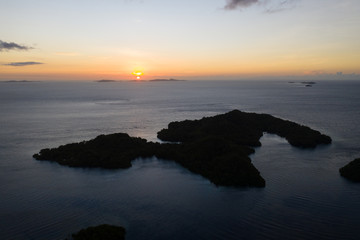 Fototapeta premium The last light of day illuminates the tranquil waters of Raja Ampat, Indonesia. This region is thought to be the center of marine biodiversity and is a popular area for diving and snorkeling.