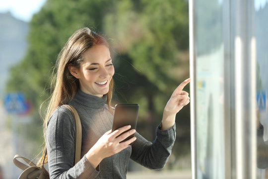 Commuter checks phone and schedule table in a bus stop