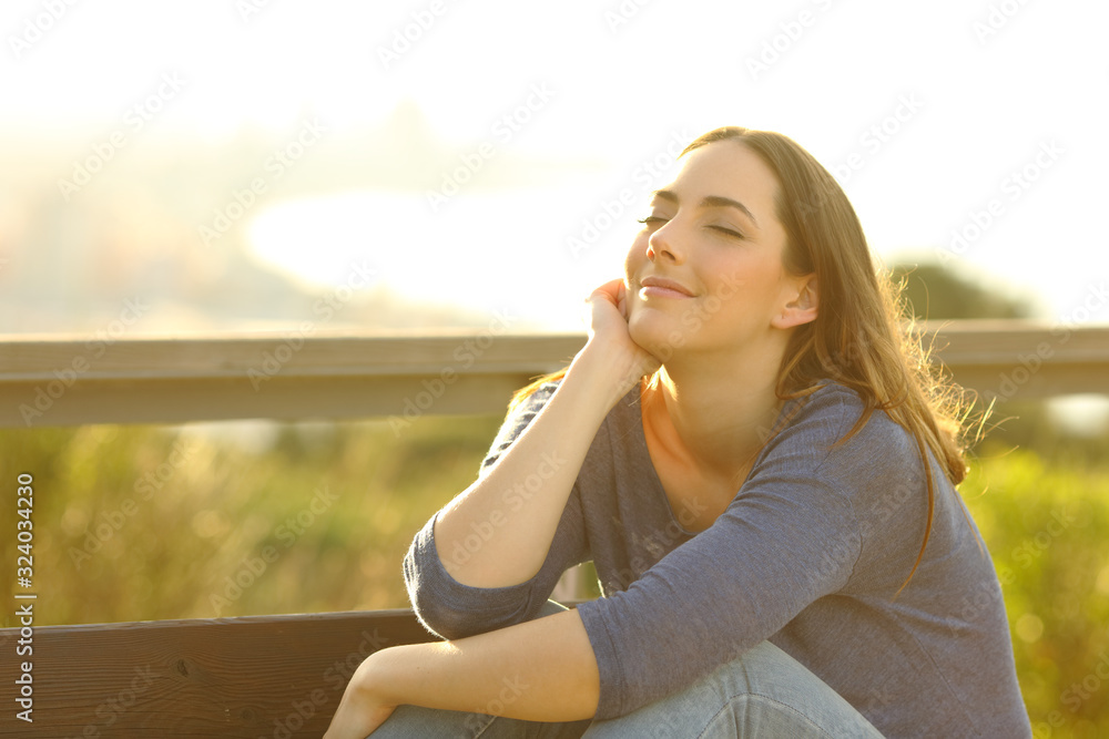 Poster Woman relaxing sitting on a bench at sunset