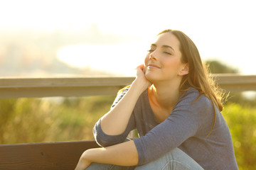 Woman relaxing sitting on a bench at sunset
