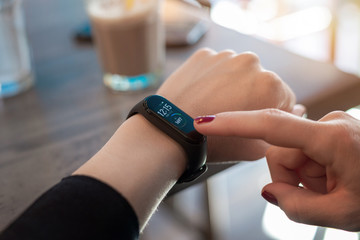 Woman use apps on smart bracelet. Tocuh display with right hand