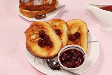 French toasts on a pink table with breadcrumbs. Fried bread with milk and scrambled eggs, concept of a modern bakery. Healthy traditional french breakfast.