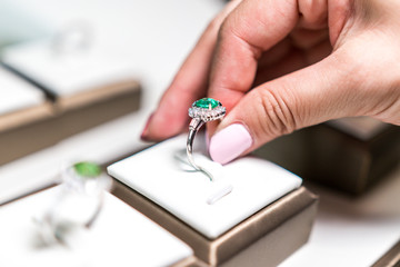 White hand picking up wedding emerald ring in a box