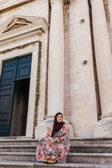 Portrait of beautiful woman with hijab standing in front of old church, historical building,  in Dubrovnik, Croatia. 