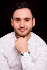 Portrait of a handsome guy on black background. Pensive pose.