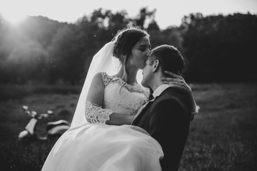 Happy bridegroom raises bride in summer park. man raised and hug woman to her arms. Newly wedded couple in the park. Just married. Walk in the park and hug. Newlyweds having fun. rustic wedding