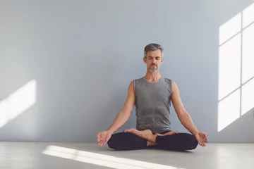 Zelfklevend Fotobehang Yoga meditation relaxation. A man practices yoga on the floor in the room. © Studio Romantic