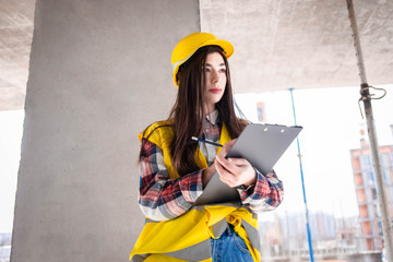 Pretty woman worker inspects the workflow at construction site, filling out documents