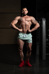 Handsome Muscular Man Flexing Muscles In Gym