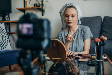 Young woman filming her make up routine. Young social media influencer filming her make up routine