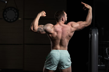 Fototapeta na wymiar Muscular Men Is Hitting Rear Double Bicep Pose