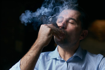 portrait of hansome man smoking cigar in a lounge bar