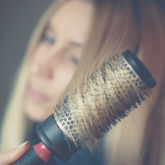 Girl with round brushing combs her long blond hair.