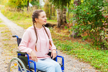 Fototapeta na wymiar Young happy handicap woman in wheelchair on road in hospital park waiting for patient services. Paralyzed girl in invalid chair for disabled people outdoor in nature. Rehabilitation concept.