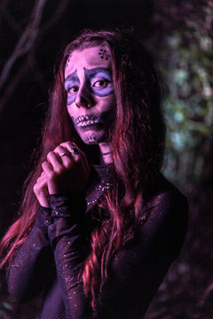 Halloween, portrait of a young woman dressed as a Mexican skull with purple lighting