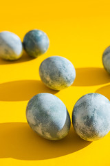 Blue textured colored Easter eggs on a bright yellow holiday background backdrop. Spring holiday concept. Copyspace. Flat lay. Top view.