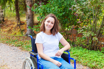 Fototapeta na wymiar Young happy handicap woman in wheelchair on road in hospital park waiting for patient services. Paralyzed girl in invalid chair for disabled people outdoor in nature. Rehabilitation concept.