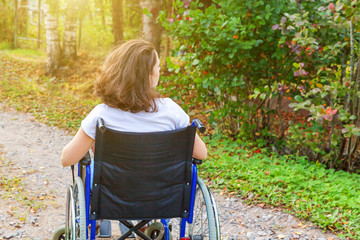 Young happy handicap woman in wheelchair on road in hospital park enjoying freedom. Paralyzed girl...