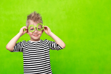 Little smiling caucasian boy in mask of leprechaun shamrock clover glasses for irish St. Patrick's...