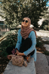 Woman with hijab sitting and looking at beautiful old city of Trebinje and Trebisnjica river, Bosnia and Herzegovina. Reflections of city on river.  September, 2018.