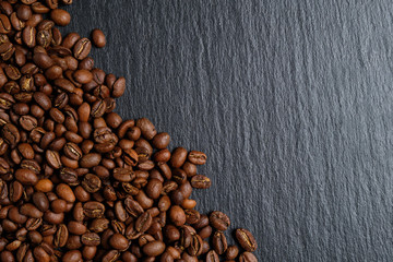 A lot of coffee beans laid out on slate with place for copy space. Top view.