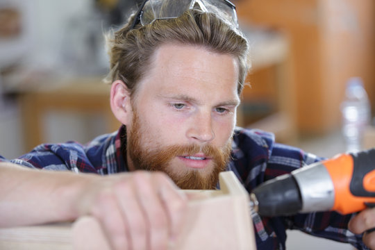 man screwing a screw into the wood elemen