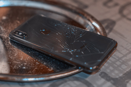 ST. PETERSBURG, RUSSIA - MAY 27, 2018: Black Smartphone Iphone X Broken Glass On The Back Cover Of The Phone Close Up