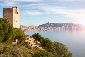 Fototapeta na wymiar Panorama of Benidorm with famous skyscrapers on the horizon and an old tower in the foreground, Spain