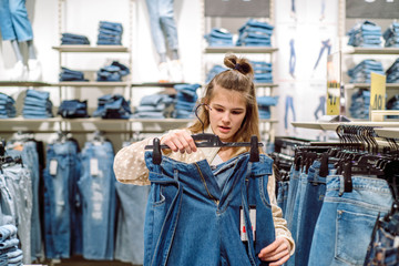 Fototapeta na wymiar Woman choosing jeans in clothing store. teen girl buys jeans in the mall. Big sale, black friday.