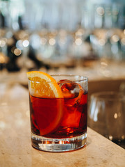 Red alcohol cocktail in glass with orange and ice