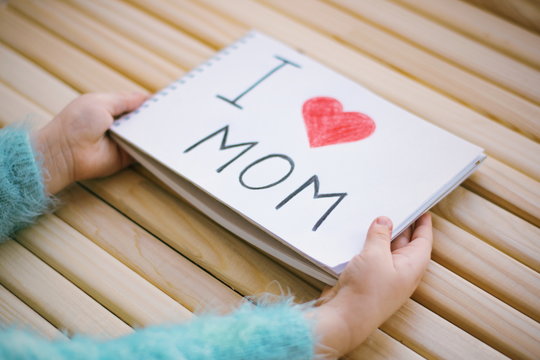  handmade greeting card for mother in the childs arms. I love mom picture. Lettering i love mom. Mother's day. 8 march.