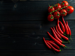 Cherry tomatoes and chilli on a black wooden table