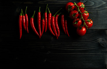 Cherry tomatoes and chilli on a black wooden background