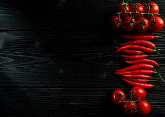 Cherry tomatoes and chilli on a black wooden background