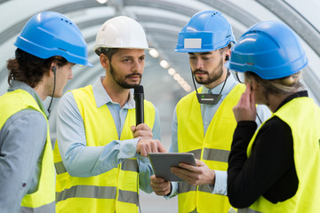 workers looking at tablet and listening to speaker through earphones