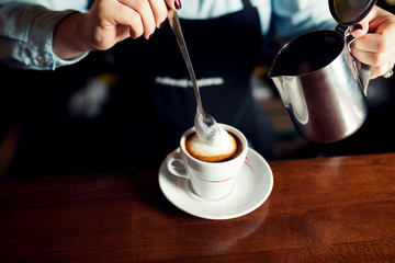 Female barista make cappuccino close up