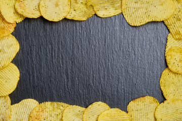 Chips are framed on a slate dish. Top view. Copy space.